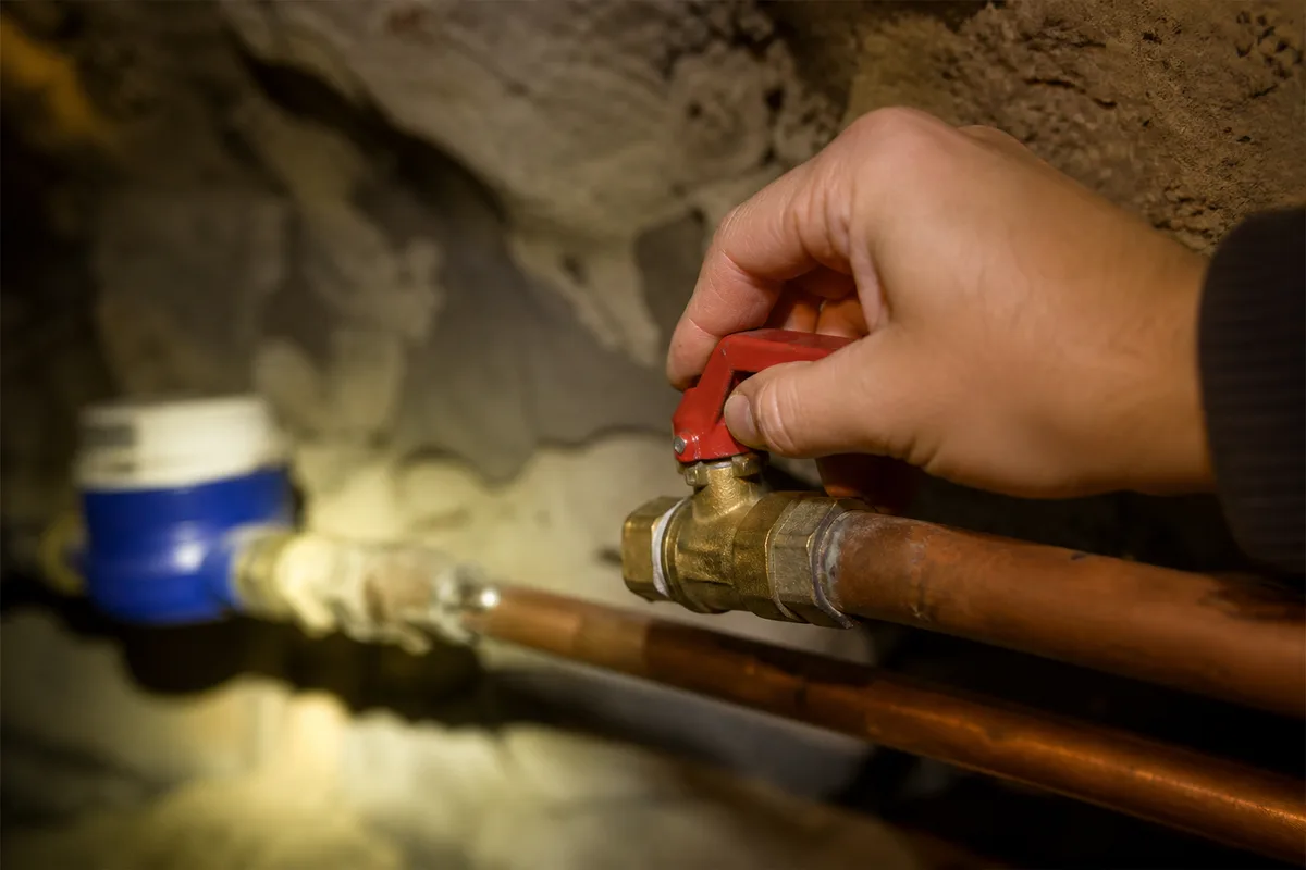 Main fermant la vanne d’arrivée d’eau générale dans une cave voûtée en pierre