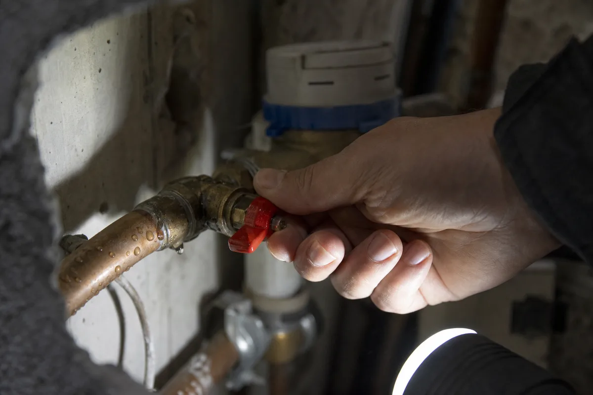 Main fermant la vanne d&rsquo;arrivée d&rsquo;eau générale près d&rsquo;un compteur dans un logement