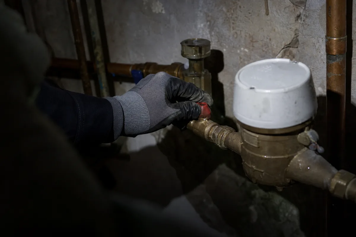 Main coupant le robinet d’arrivée d’eau générale près d’un compteur